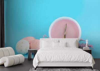 An Easter egg and pink alarm clock on blue background Wall mural