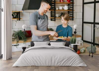 family dad young man and son teenage boy cook vegetable salad in kitchen and spend quality time together, father and son talking and cooking vegetarian food and doing chores, 8 march and mothers day Wall mural