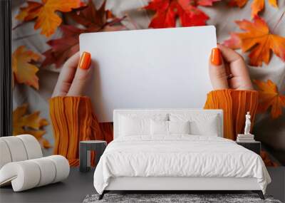 woman holding a blank white card with colorful fall leaves background Wall mural