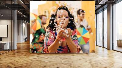 Brazilian Carnival. Young woman enjoying the carnival party blowing confetti Wall mural