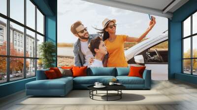 Family road trip. Latin family traveling locally by car. Taking self portrait on smartphone Wall mural