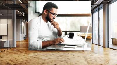 Focused man working on his laptop at home Wall mural