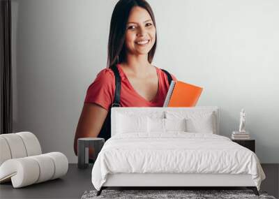 Portrait of a cheerful smiling african student girl wearing backpack and holding books isolated over white background Wall mural