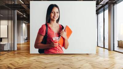 Portrait of a cheerful smiling african student girl wearing backpack and holding books isolated over white background Wall mural