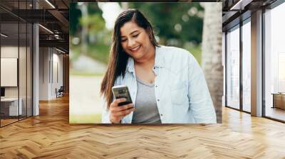 Portrait of beautiful plus size woman using her smartphone outdoors Wall mural