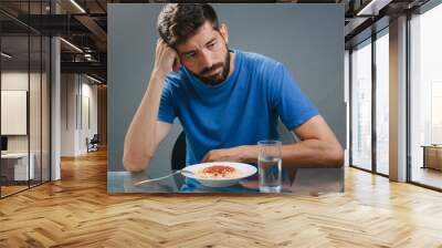 portrait of man with no appetite in front of the meal. concept of loss of appetite Wall mural