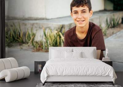 Portrait of teen boy sitting on skateboard Wall mural