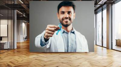 Prostate Cancer Awareness. Doctor man holding light Blue Ribbon for supporting people living and illness. Men Healthcare and World cancer day concept Wall mural