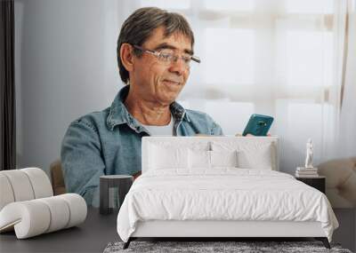 Senior man using smartphone at home Wall mural