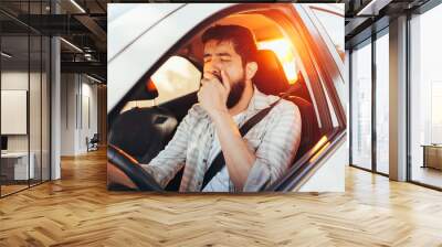 Tired man yawning while driving his car Wall mural