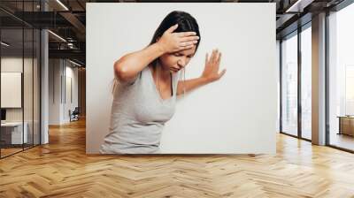 Woman suffering from dizziness with difficulty standing up while leaning on wall Wall mural