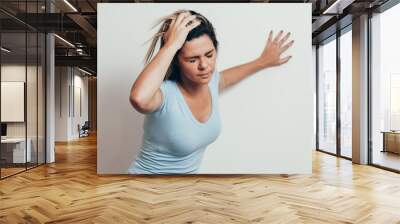 Woman suffering from dizziness with difficulty standing up while leaning on wall Wall mural