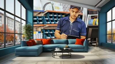 Young latin man working in hardware store Wall mural