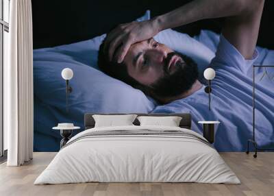 Young man in bed with eyes opened suffering insomnia and sleep disorder Wall mural