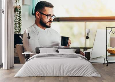 Young man working from home on his laptop Wall mural