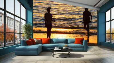 Silhouette of friends on tropical beach in beautiful sunset. Wall mural