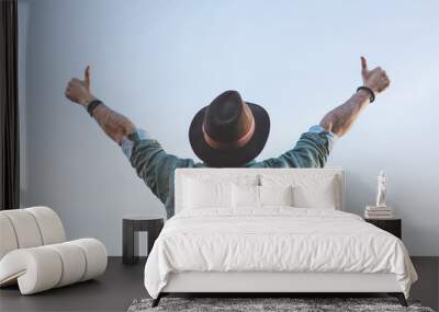 Handsome happy bearded hipster looking at blue sky and gesture his hands in ok symbol. People Watching concept Wall mural