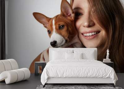 Handsome redhead hair young female hugging and kissing her puppy basenji dog. Love between dog and owner. Isolated on white background. Wall mural