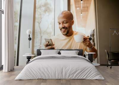 happy cheerful african hipster holding mug, drinking fresh cappuccino, browsing internet and checkin Wall mural