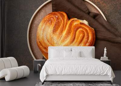 A bun with sugar in the shape of a heart in a plate on a dark culinary background. delicious homemade pastries top view Wall mural