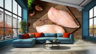 Chicken breast fillet on a wooden Board on a brown wooden table. Raw chicken breast. Top view with space for text Wall mural