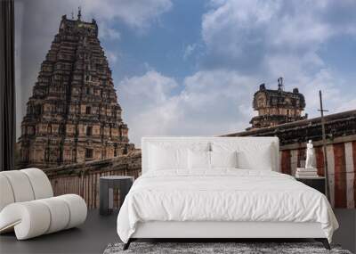 Hampi, Karnataka, India - November 4, 2013: Virupaksha Temple complex. Red and white wall around said complex under blue cloudscape. East and central gate Gopurams visible over it. Wall mural