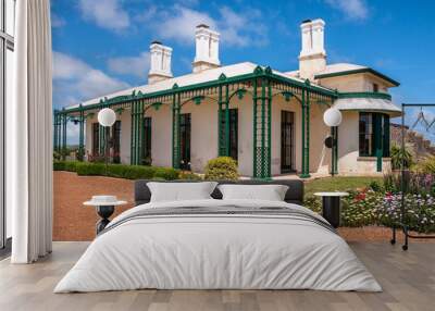 Stanley, Tasmania, Australia - December 15, 2009: Hightfield Historic Site. Closeup of White with green trim main house with tall chimneys with flowers up front under blue cloudscape. Wall mural