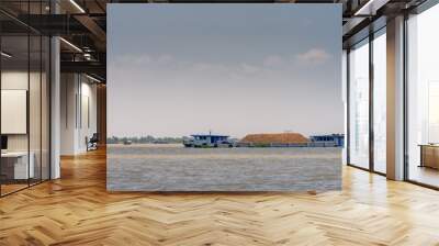 Tan Phong, Mekong Delta, Vietnam - March 13, 2019: Closeup of Blue modern barge filled to top with brown sand on Mekong River under light blue sky.  Wall mural