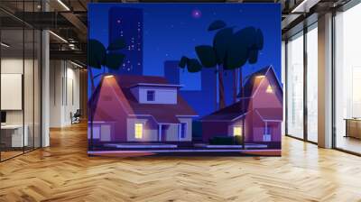 Street in suburb district with residential houses and city on skyline at night. Vector cartoon landscape illustration suburban cottages with garages, trees and road in dusk and electrical lamp light Wall mural