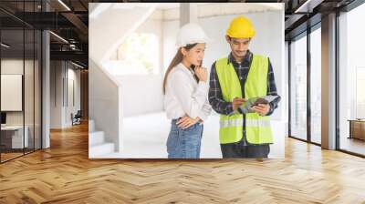 Builder team, foreman asian young engineer, architect man, woman working, discussing construction drawing on clipboard follow project to build industrial plan at house site. Engineering worker people. Wall mural