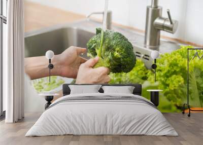 Close up asian young woman washing broccoli, tomato, carrot fresh vegetables, paprika with splash water in basin of water on sink in kitchen, preparing fresh salad, cooking meal. Healthy food people. Wall mural