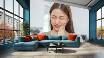 Closing eyes asian young woman touching cheek, face expression from toothache, tooth decay or sensitivity, Having tooth or teeth problem or inflammation, suffering from health. Sensitive teeth people Wall mural