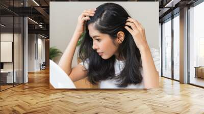 Damaged hair symptom, problem hair fall asian young woman, girl worry about balding, looking at scalp in mirror, hand in break into front hair loss, thin problem. Health care treatment for beauty. Wall mural