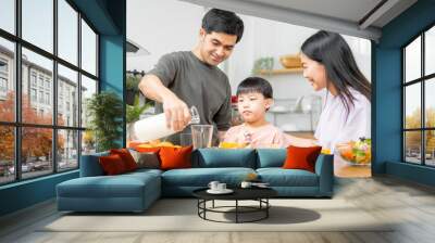 Happy refreshment family breakfast in morning, asian young parent father, mother and little cute boy, child having meal in kitchen eating together at home. Cheerful, enjoy cooking people. Wall mural