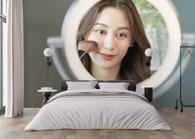 Happy routine beauty concept, pretty asian young woman, girl make up face by applying powder foundation by brush around face, looking at the mirror at home. Female look with natural fashion style. Wall mural