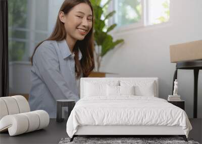 Pretty, Smile owner business asian young woman holding packing, box by tape machine, sealing cardboard indoors. Business owner in warehouse, Moving or preparing in new house, apartment or relocation. Wall mural