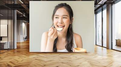 Protein in food, happy smiling asian young woman, girl in diet eat boiled egg, hand holding spoon put food in mouth with for breakfast in the morning at home. Health care, loss weight people concept. Wall mural