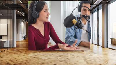 Smile two asian young woman, man radio hosts in headphones, microphone while talk, conversation, recording podcast in broadcasting at studio together. Technology of making record audio concept. Wall mural