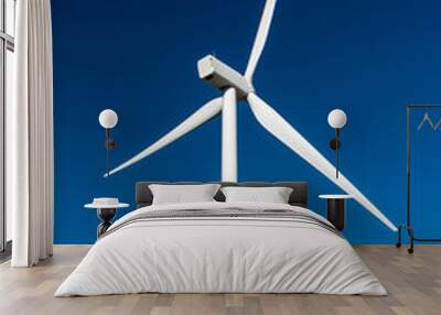 Close-up of two white wind turbines against a deep blue sky background Wall mural