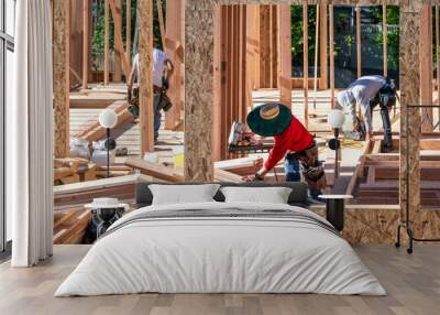 Construction work crew building a new house in a residential neighborhood, wood framing started, sunny summer construction season
 Wall mural