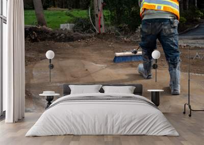 Construction worker with push broom cleaning dirt off road from stump removal during a road construction project
 Wall mural