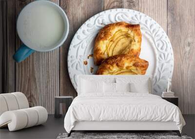 Fresh individual apple tarts on a white plate, blue cup of milk, wood background Wall mural