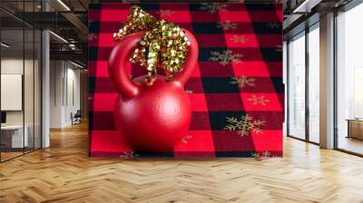 Holiday fitness, red kettlebell on a holiday background of red and black with gold snowflakes, gold ribbon Wall mural