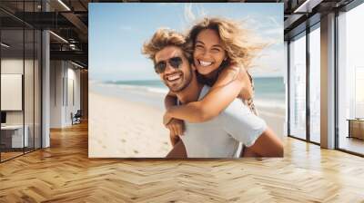 Beautiful young couple in sunglasses having fun on the beach. Man piggybacking his girlfriend. Wall mural