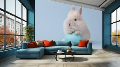 Easter bunny rabbit with blue painted egg on blue background. Easter holiday concept. Wall mural