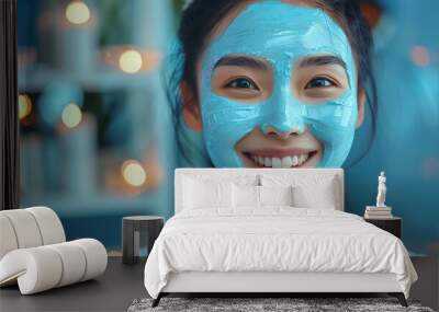 Smiling woman with blue face mask enjoying a spa day at home, surrounded by soft lights and a cozy atmosphere. Wall mural