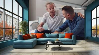 Sofa, old man and adult son bonding together in living room, conversation and support in home. Love, relationship and senior dad with man on couch, relax and discussion, family connection and advice. Wall mural