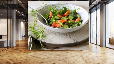 plate with salad with cucumbers, green peas and salmon on a light table Wall mural