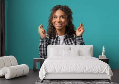 African teenager girl praying crossed fingers on blue. Young adult begs someone Wall mural