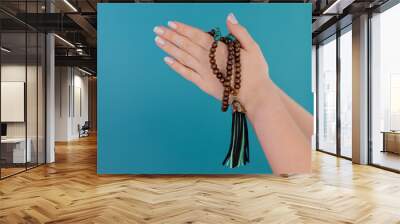 Praying woman on blue background, meditating, reading mantras, directs thoughts, requests or gratitude to universe. Isolated. Spirituality, religion, God concept. Wall mural